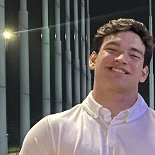 Jaxson Sebanc, head and shoulders, photographed at night: his face lit warm against a dark background, looking just off camera.